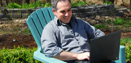 Man sitting outside looking at laptop